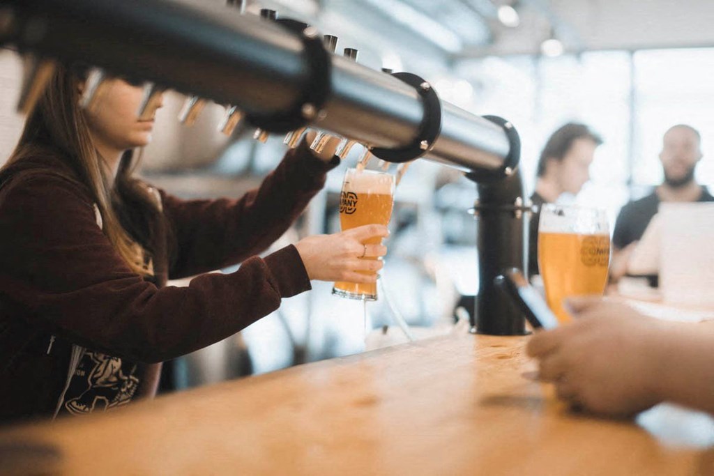 a woman pouring beer into a glass at a bar