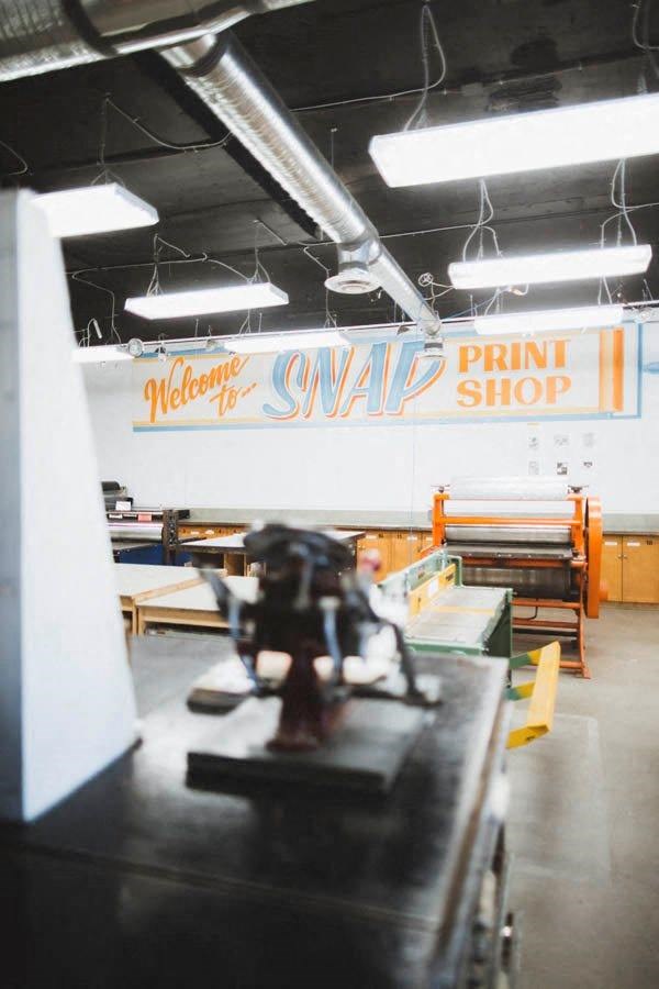 a printing shop with a machine and a sign on the wall