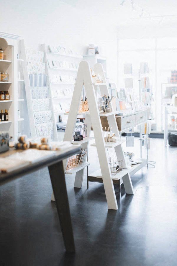 a display case in a white store with shelves and tables