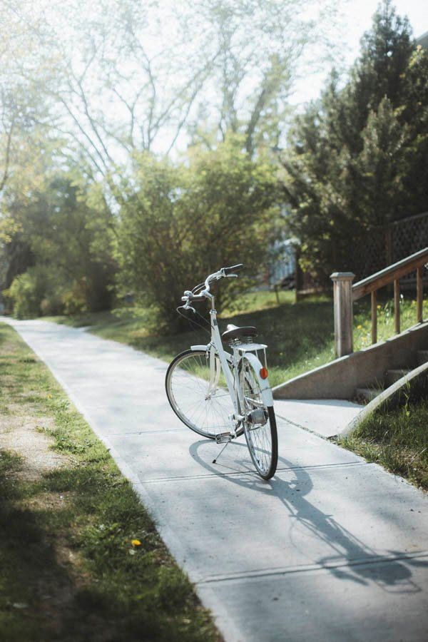 a white bike parked on the side of a sidewalk