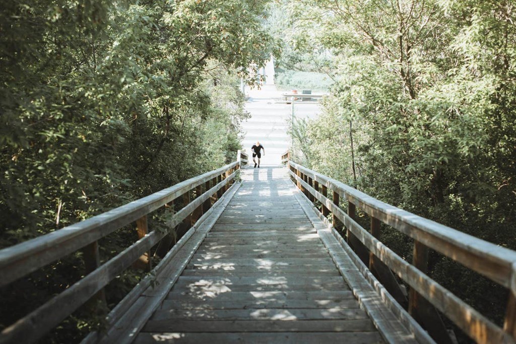 two people walking across a wooden bridge