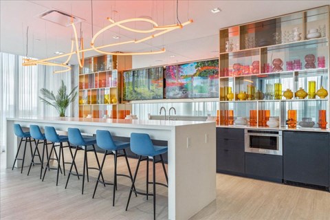 A modern kitchen with a bar area and blue chairs.