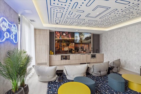 A room with a neon sign, a potted plant, and a large window.