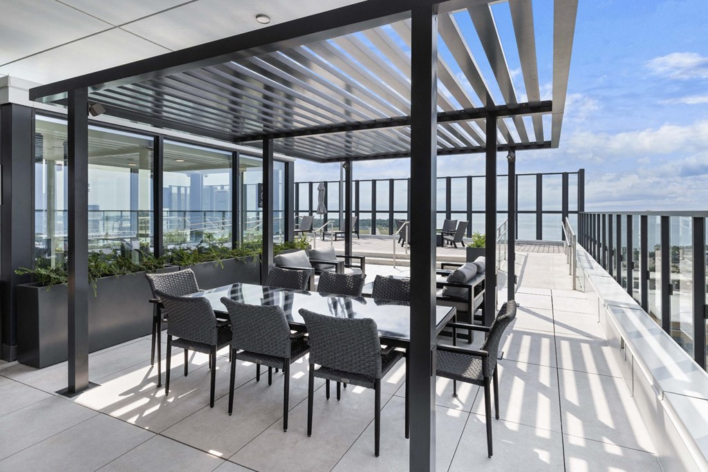 a dining area with a table and chairs on a balcony overlooking the ocean