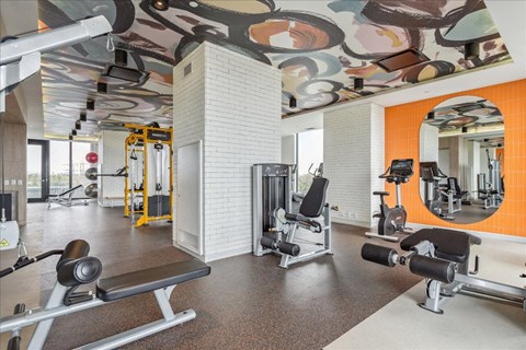 A gym with a variety of equipment including a bench press, a squat rack, and a mirror.