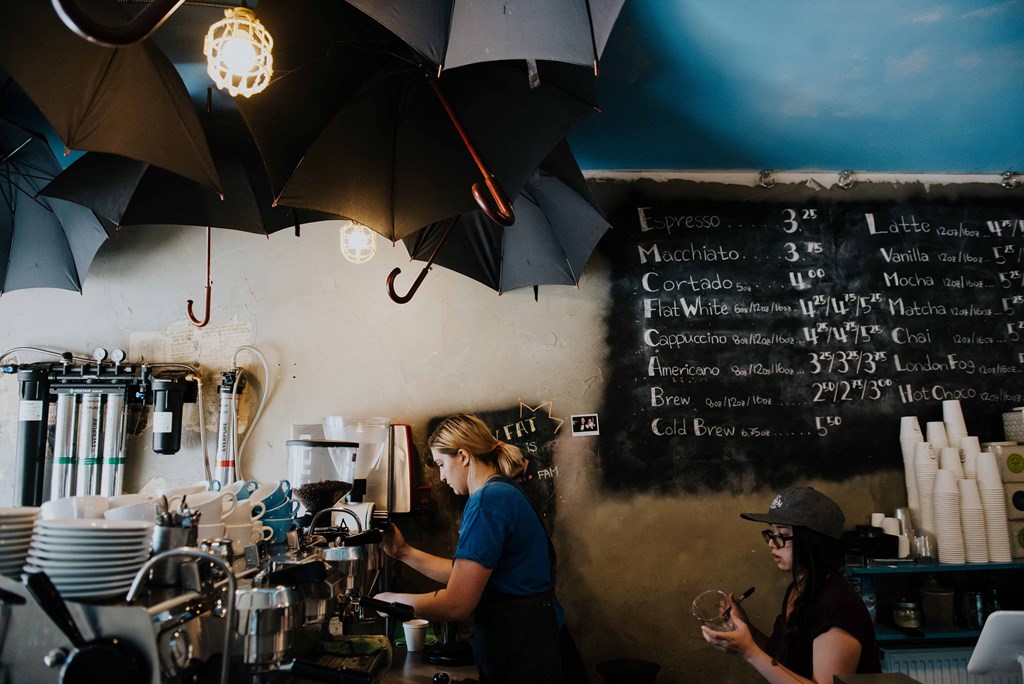 two women working at a coffee shop with umbrellas on the wall