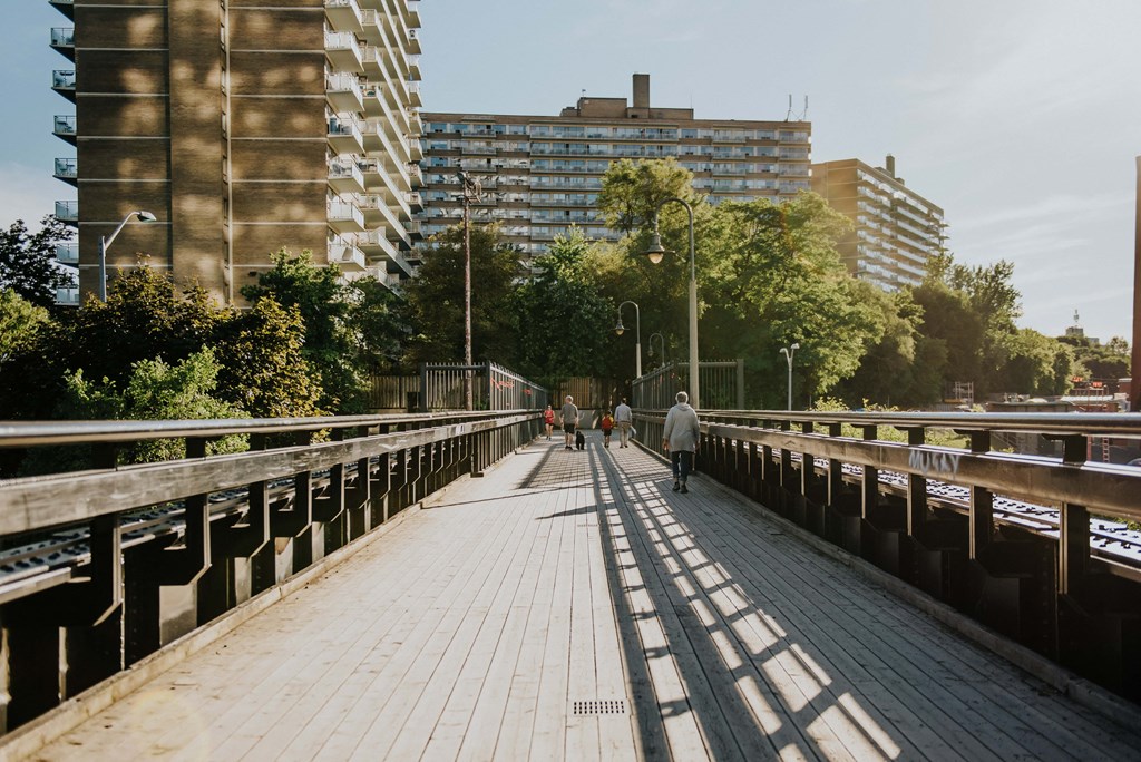 people walking on a wooden bridge over a river in a city