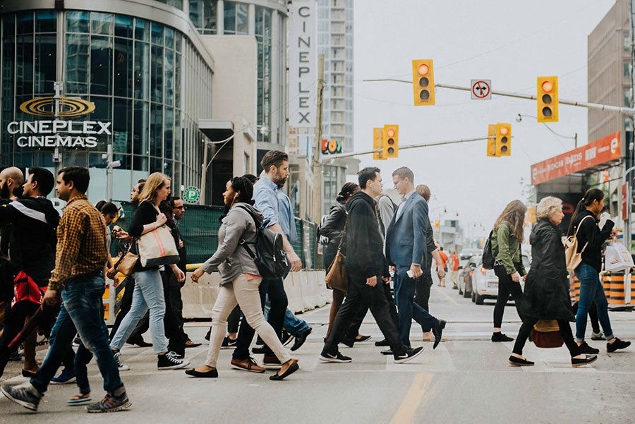 people crossing a busy city street at a traffic light