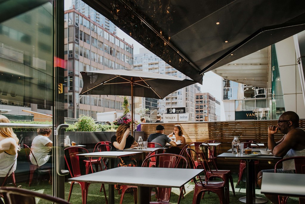 people sitting at tables outside of a restaurant