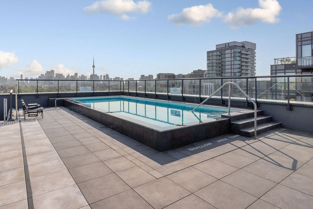 a rooftop swimming pool on the top of a building with a city in the background