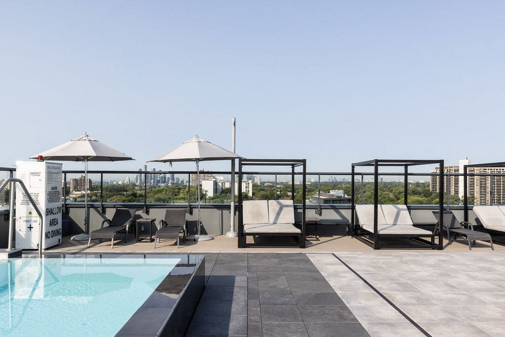 a rooftop pool with lounge chairs and umbrellas
