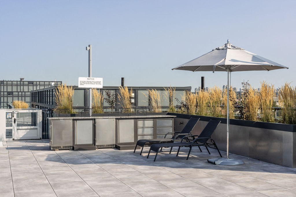 a roof terrace with two lounge chairs and an umbrella