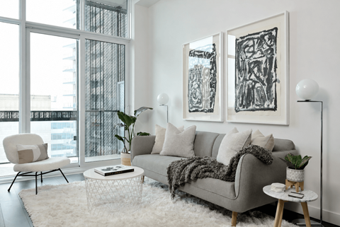 A living room with a grey couch, a white chair, a white coffee table, and two framed artworks on the wall.