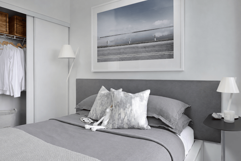 A bedroom with a large bed, a nightstand with a lamp, and a picture hanging above the bed.