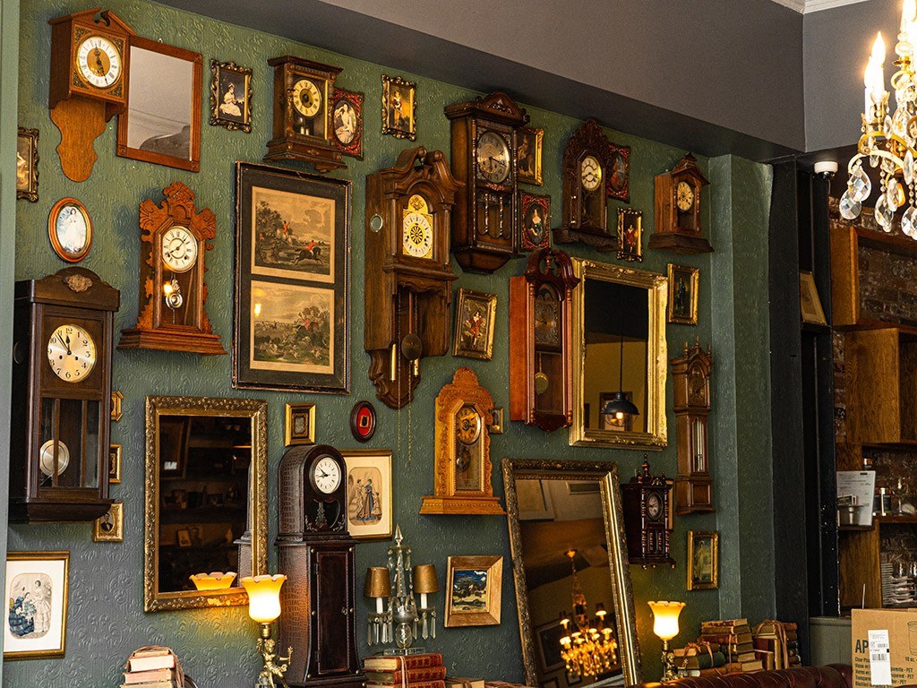 a wall full of clocks and mirrors in a room