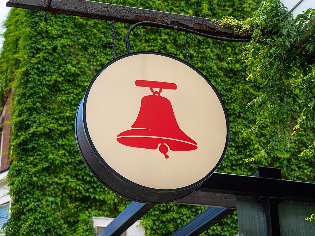 a red bell sign hanging from a green wall