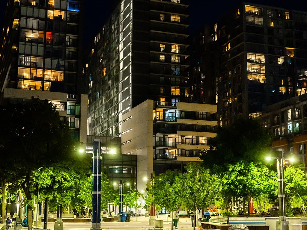 a city street at night with tall buildings and trees