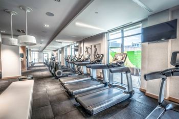 a gym with cardio equipment and a row of exercise machines