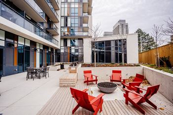 a courtyard with red chairs and a fire pit