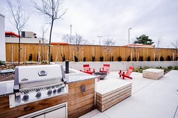 the backyard has a barbecue grill and a patio with red chairs