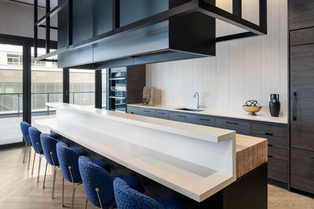 a kitchen with a long white counter top and blue chairs