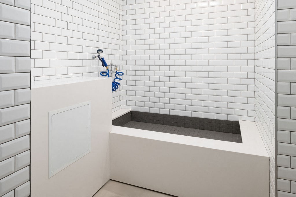 a white bathroom with a sink and white tiled walls