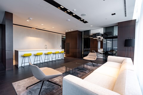 A modern living room with a white sofa and yellow bar stools.