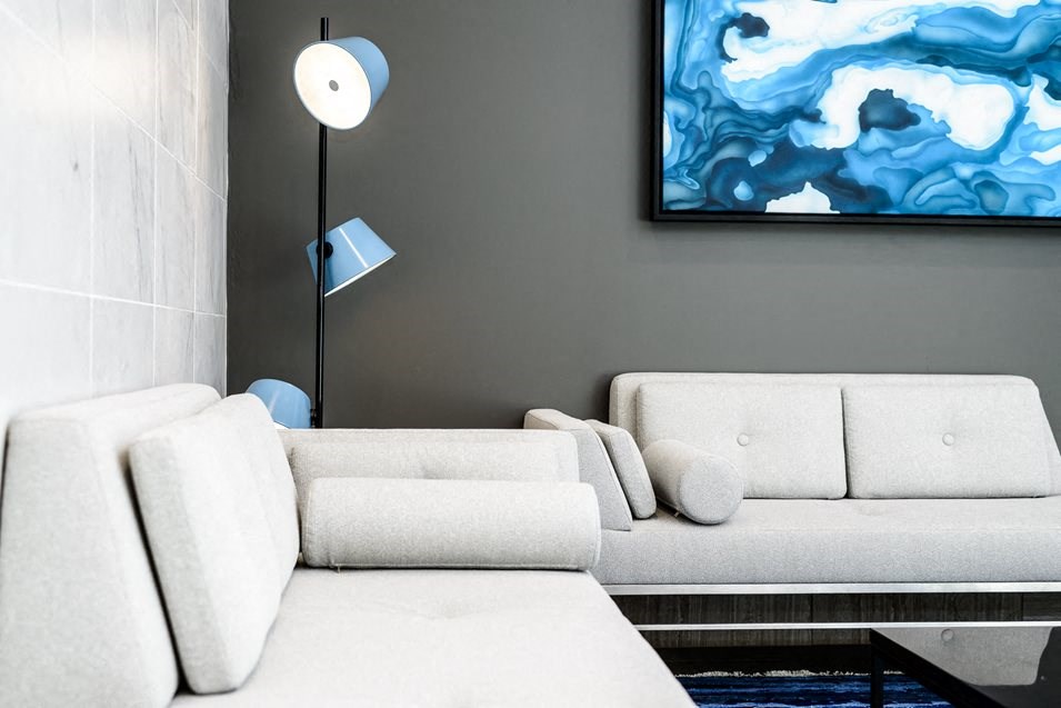 a living room with a white couch and a blue painting on the wall