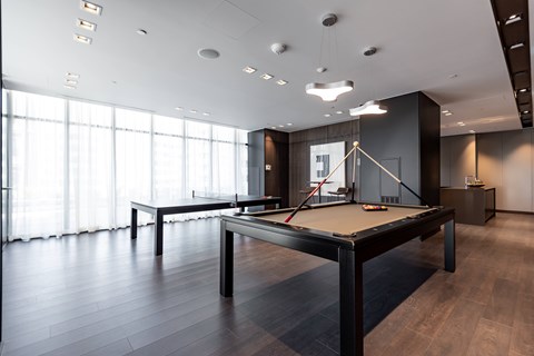 A pool table in a room with wooden floors and a large window.