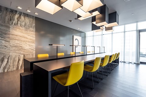 A modern dining room with yellow chairs and a marble wall.