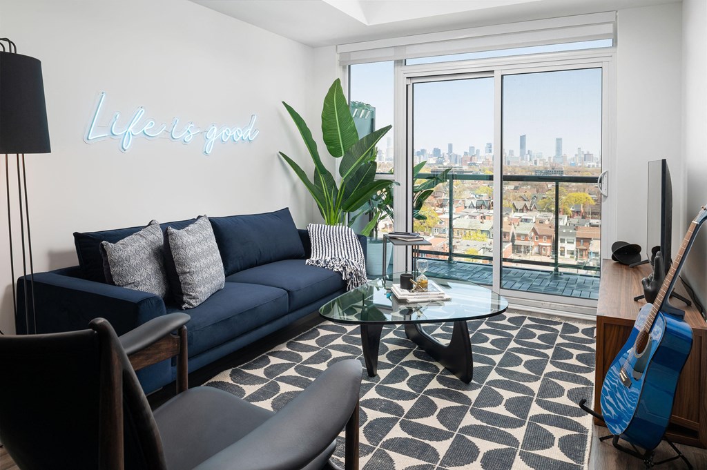 a living room with a blue couch and a glass coffee table and a large window