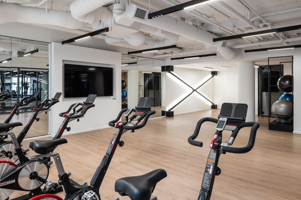 a gym with cardio bikes and a tv on the wall