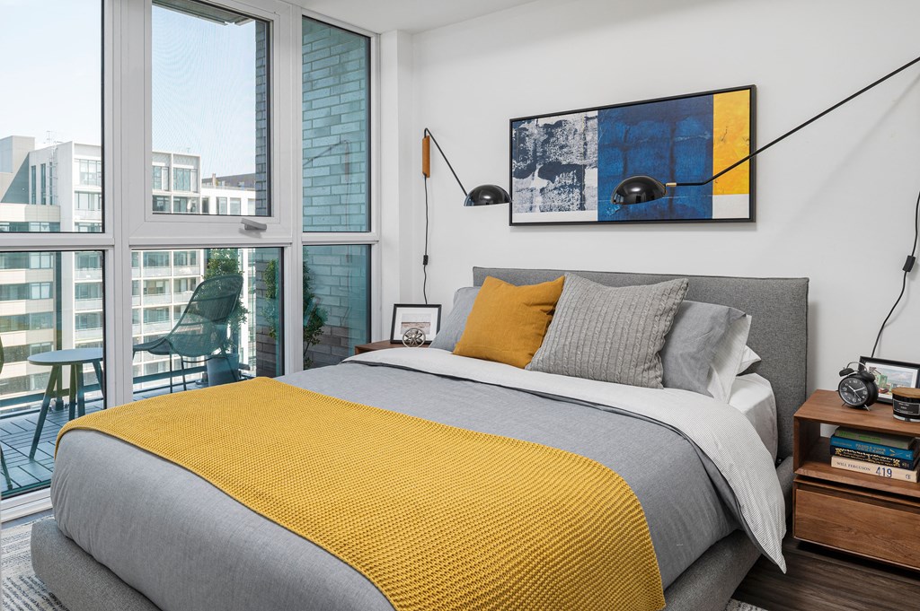 a bedroom with a large window and a bed with a yellow blanket