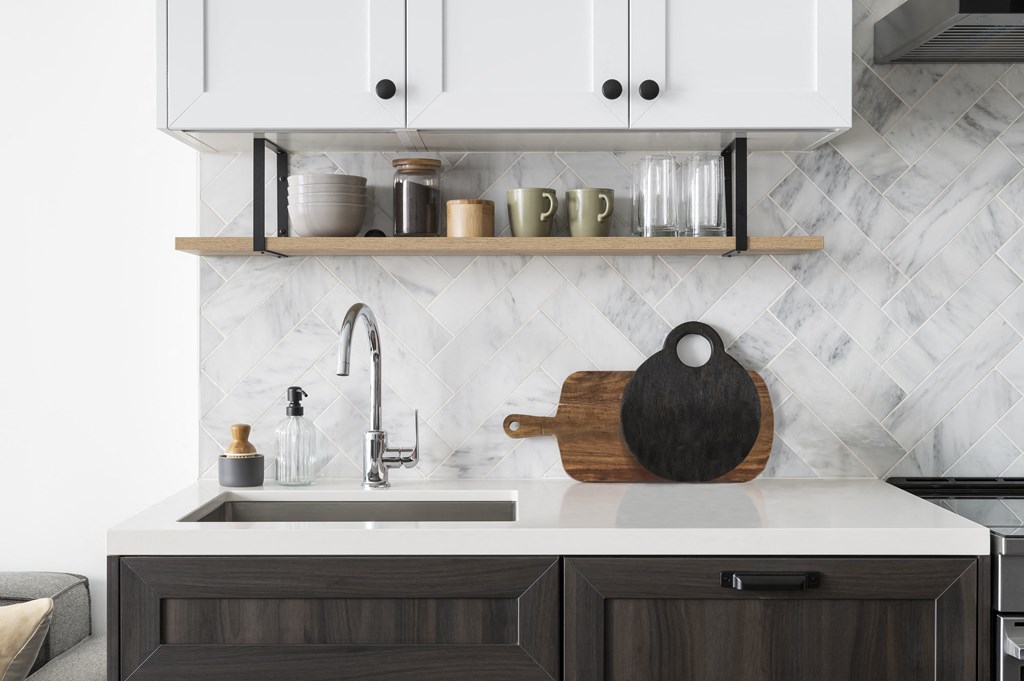 a kitchen with white cabinets and a sink and a wooden cutting board