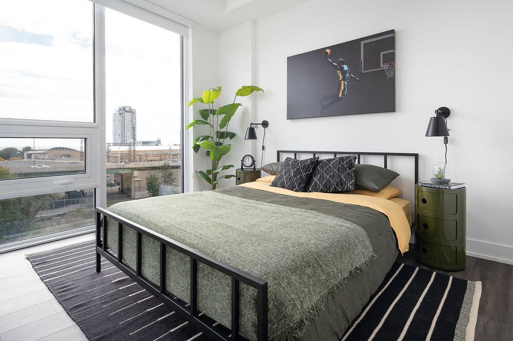 bed with green sheets and painting above headboard