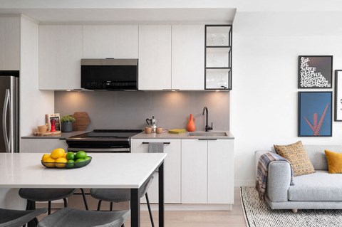 a kitchen with white cabinets and a table with a bowl of fruit