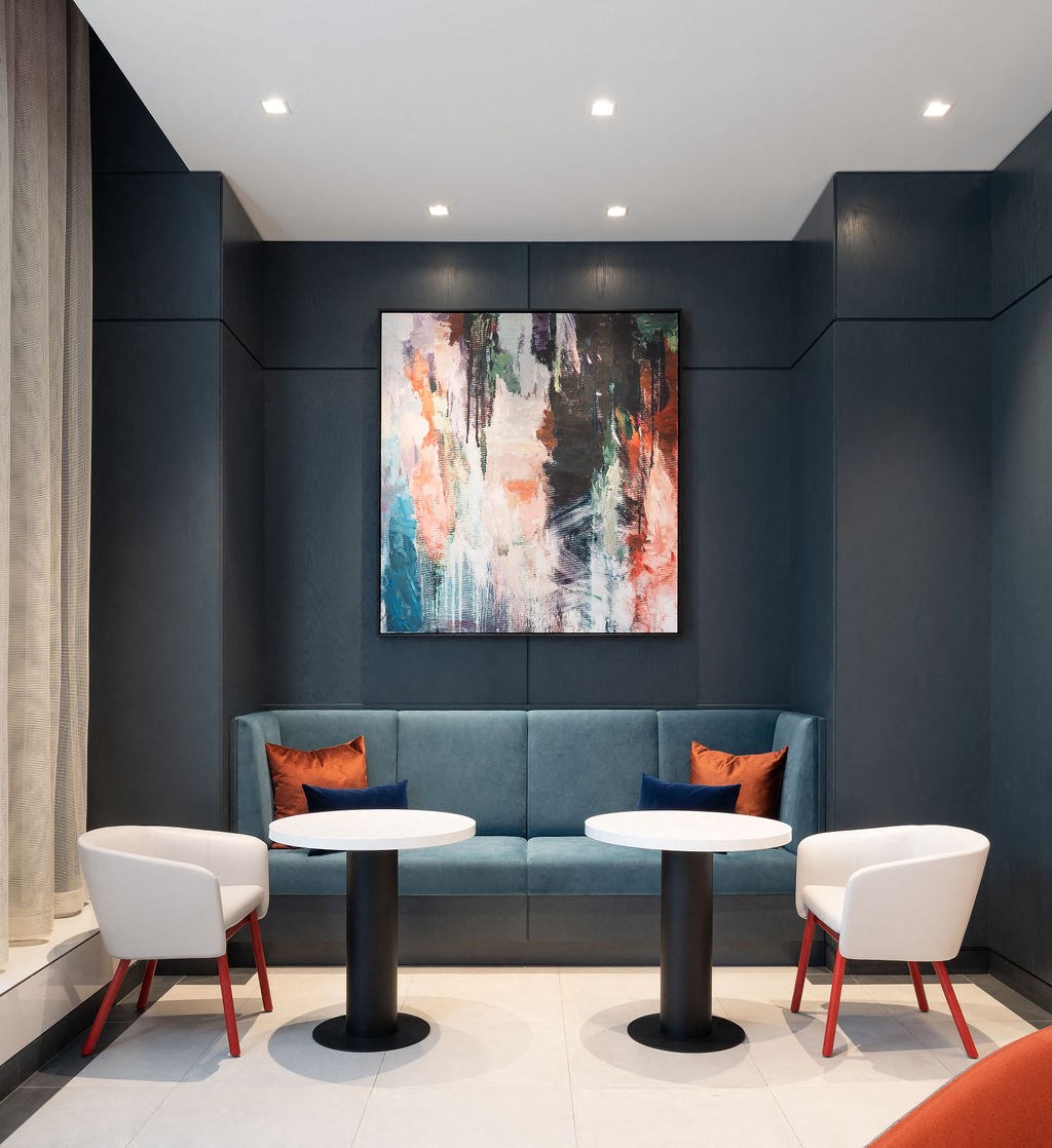 a lounge area with tables and chairs and a painting on the wall