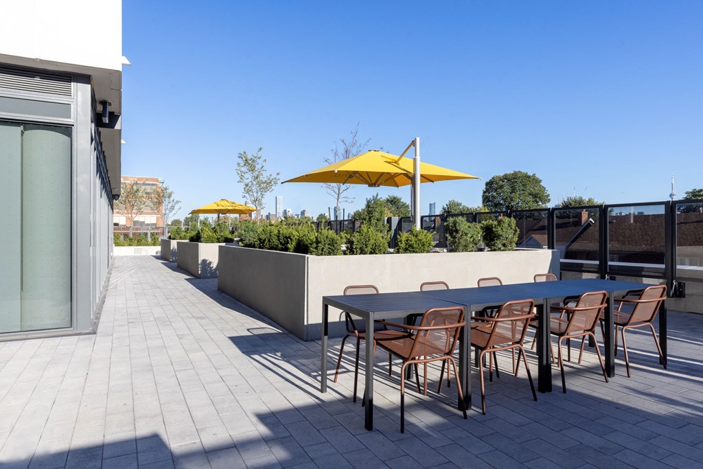 a terrace with a table and chairs with yellow umbrellas in the background