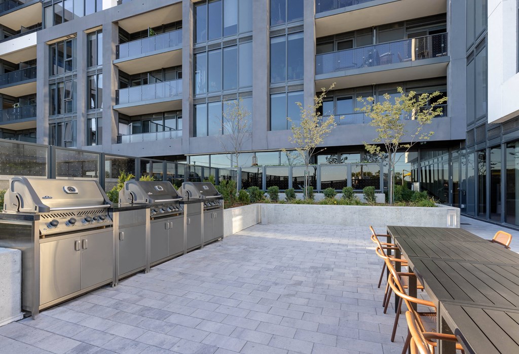an outdoor patio with barbecue grills and a wooden table and chairs