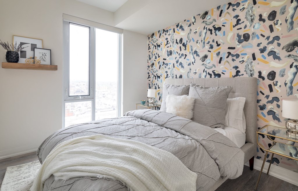a bedroom with a bed and a wall with a graphic wallpaper