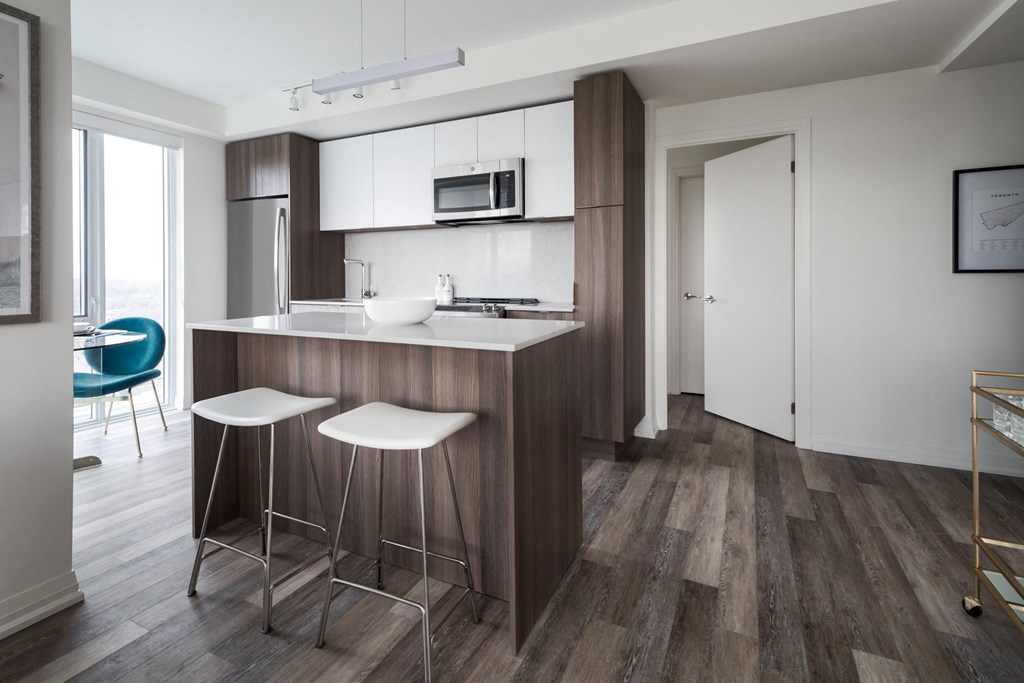 a kitchen with white cabinets and a counter with two stools
