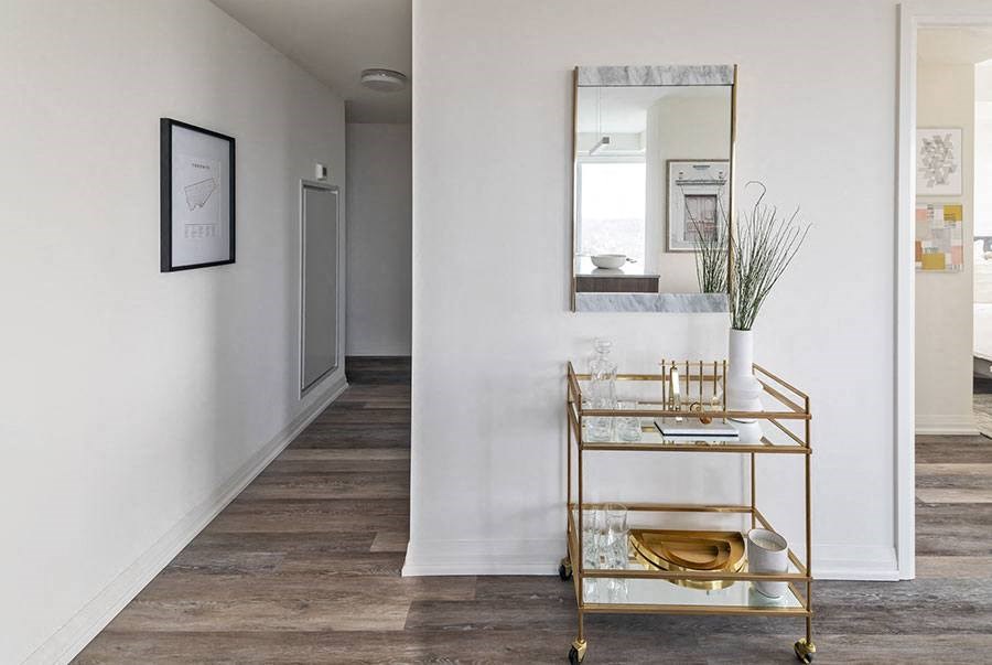 a hallway with a mirror and a table with a vase