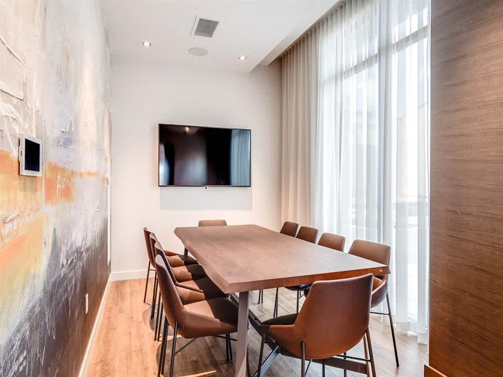 a conference room with a table and chairs and a television