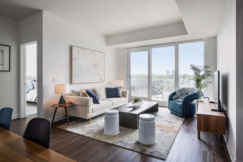 A living room with a couch, a chair, a coffee table, and a large window.