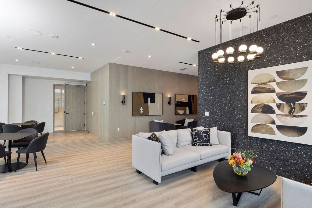 A modern living room with a grey sofa, a black coffee table, and a dining table with chairs.