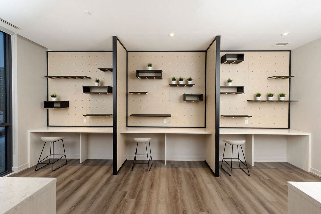 A room with a white table and black stools.