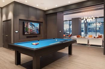 A pool table with a television in the background.