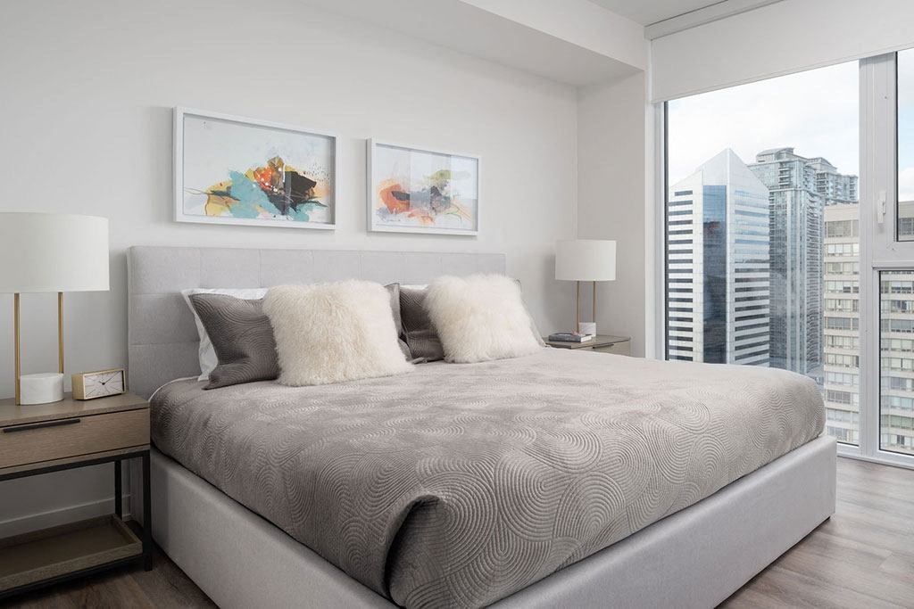A bedroom with a large bed and two framed pictures on the wall.