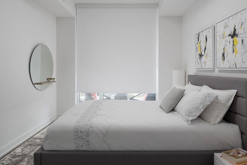 A bedroom with a large bed and a round mirror on the wall.