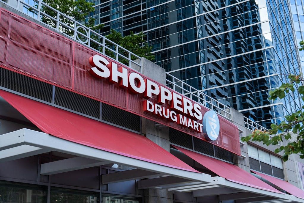 a sign for shoppers drug mart in front of a tall building